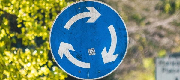 Ein rundes Schild mit weißen Pfeilen auf blauem Hintergrund 